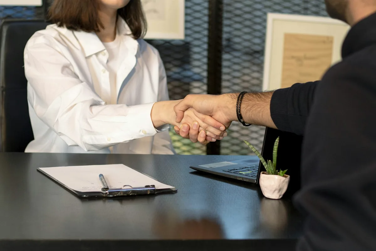 A client and attorney shaking hands across a desk after a positive case experience.